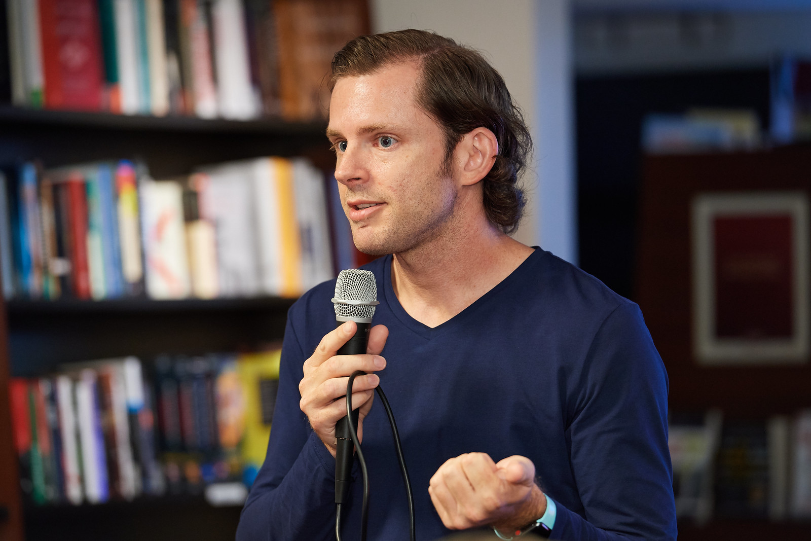 Chris Guillebeau speaking at a bookstore event, microphone in hand