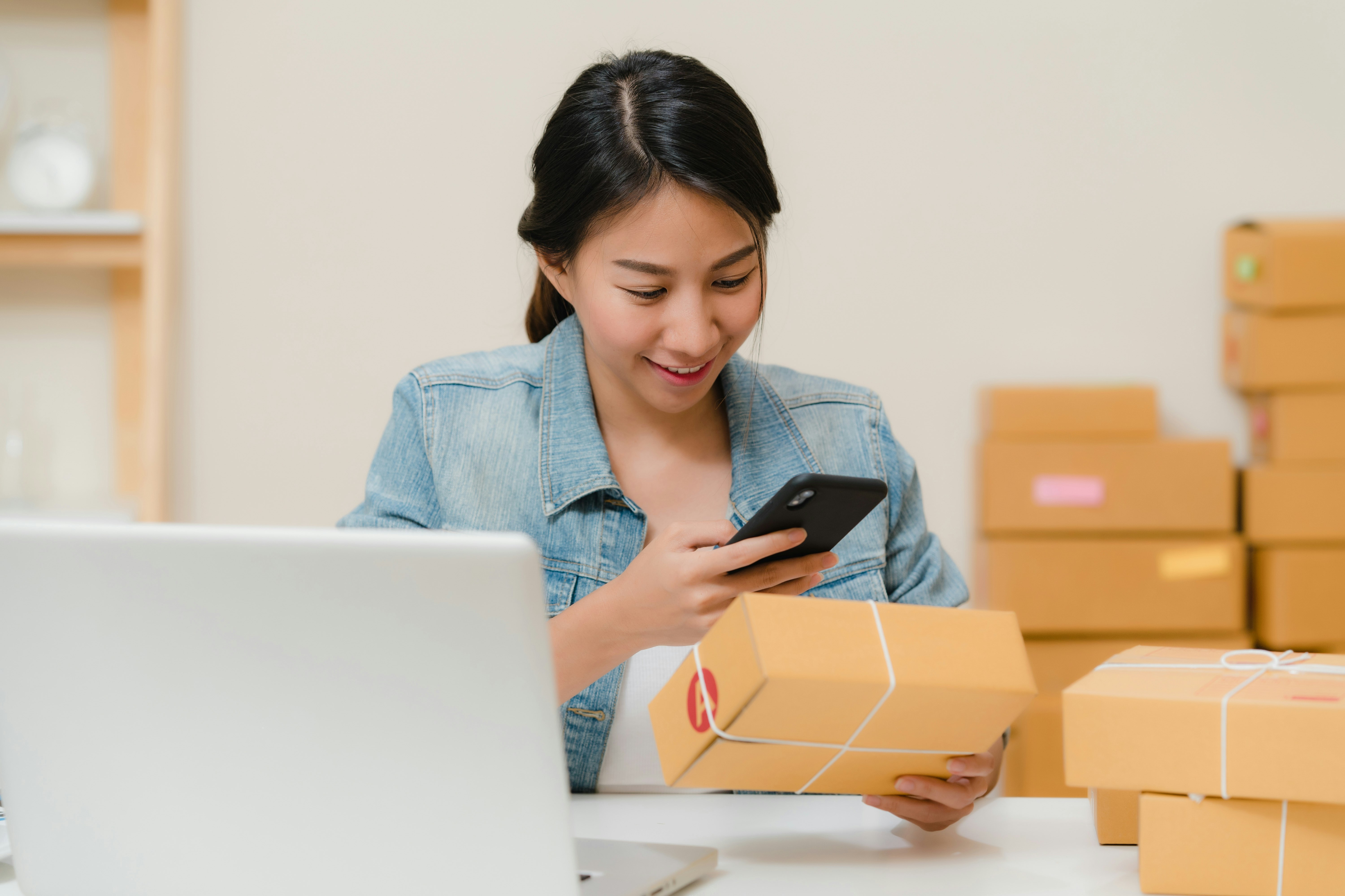 Woman checking a package order on her phone—shipping a product without a sales call